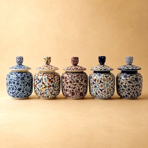 Puede incluir: Cinco tarros de cerámica con tapa, cada uno con intrincados patrones florales. Los tarros muestran varios esquemas de color, incluyendo azul y blanco, diseños florales multicolores, rojo oscuro y patrones con acentos azules y motivos botánicos.