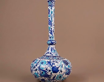 May include: A tall ceramic vase with a bulbous base and a slender, elongated neck. The surface is decorated with intricate floral patterns in shades of cobalt blue, turquoise, and white, featuring stylized tulips and leaves across the entire body.