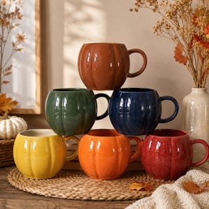 Peut inclure: Un ensemble de six tasses en céramique en forme de citrouille, chacune avec une finition brillante dans des couleurs distinctes dont marron, vert foncé, bleu marine, jaune, orange et rouge. Chaque tasse a un corps arrondi avec des nervures.