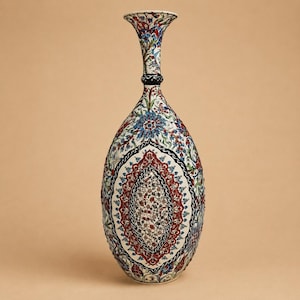 May include: A tall ceramic vase with a narrow neck and flared rim, featuring an intricate hand-painted floral pattern in shades of red, blue, green, and black on a white background, with a prominent central medallion design on the body.