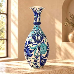 May include: A tall, teardrop-shaped ceramic vase featuring a white base decorated with intricate floral patterns in shades of cobalt blue and turquoise. The vase has a slender, flared neck and a rounded body with a detailed painted finish.