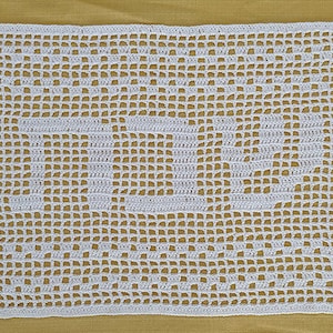 May include: White crocheted doily with a square shape and a delicate pattern. The doily is made of fine yarn and has a delicate, lacy design.