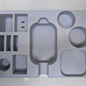 May include: A grey foam organiser with multiple compartments. The organiser has a large rectangular compartment in the centre, a smaller rectangular compartment to the left, and three round compartments to the right.