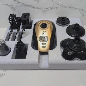 K&ouml;nnte beinhalten: Eine wei&szlig;e Schaumstoffschale mit einem schwarzen und goldenen Elektrorasierer und verschiedenen Aufs&auml;tzen. Der Rasierer hat ein schwarzes Geh&auml;use mit goldener Verzierung und den Buchstaben "F" auf der Vorderseite. Die Aufs&auml;tze umfassen einen Nasenhaartrimmer, einen Barthaartrimmer und einen Folienrasierer.