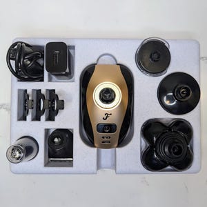 May include: A gold and black electric shaver with multiple attachments, including a nose trimmer, beard trimmer, and hair clippers. The shaver is packaged in a white box with a foam insert.