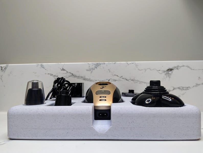May include: A set of black and gold electric grooming tools with a charging base. The tools include a nose and ear trimmer, a beard trimmer, and a facial hair trimmer. The tools are arranged in a white foam base.