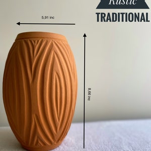 May include: A terracotta vase with a textured, geometric pattern. The vase is 8.66 inches tall and 5.91 inches wide. Modern Rustic Traditional.