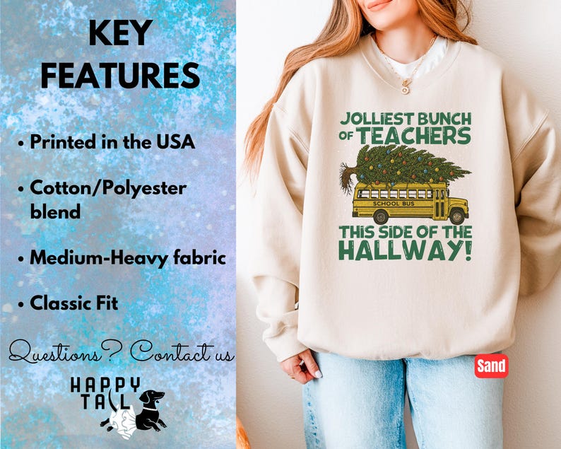 May include: A sand-colored crewneck sweatshirt featuring a graphic of a yellow school bus carrying a Christmas tree on its roof. The text reads JOLLIEST BUNCH OF TEACHERS THIS SIDE OF THE HALLWAY. The left side lists key features including printed in the USA.
