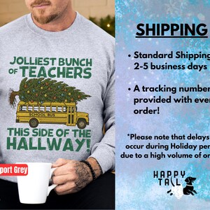 May include: A sport grey crewneck sweatshirt featuring a graphic of a yellow school bus carrying a decorated Christmas tree on its roof. The text reads JOLLIEST BUNCH OF TEACHERS THIS SIDE OF THE HALLWAY in green and black lettering.