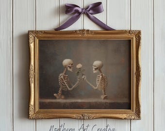 May include: A framed vintage print depicting two skeletons sharing a rose. The artwork is in a gold ornate frame and is suspended by a purple bow. The print has a dark, moody aesthetic, with the text "Northern Art Creative" at the bottom.