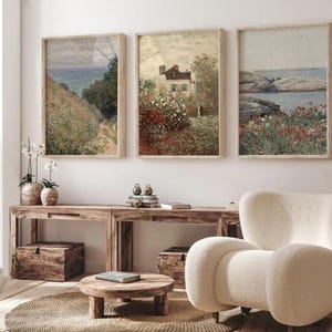 Puede incluir: Tres pinturas de paisajes enmarcadas con un tema costero. Las pinturas est&aacute;n en un sal&oacute;n con un sill&oacute;n blanco y una mesa de caf&eacute; de madera.
