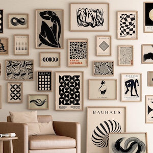Può includere: Una parete di galleria con stampe artistiche incorniciate in vari formati e stili. Le stampe presentano disegni astratti, motivi geometrici e figure minimaliste in bianco e nero. Alcune stampe includono testo come "BAUHAUS" e "YAYOI KUSAMA".