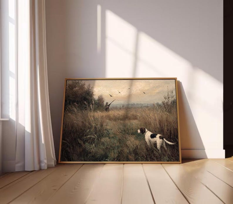 Peut inclure: Peinture de paysage encadr&eacute;e repr&eacute;sentant une sc&egrave;ne de chasse. Un chien avec des marques noires et blanches se tient dans un champ d'herbes hautes, avec un chasseur et des oiseaux en arri&egrave;re-plan. L'&oelig;uvre a une palette de couleurs chaudes et est expos&eacute;e sur un sol en bois.