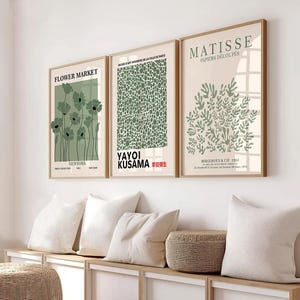 May include: Three framed art prints with a minimalist design. The prints feature green and white illustrations of flowers, abstract shapes, and leaves. The prints are titled "Flower Market", "Yayoi Kusama", and "Matisse, Papiers Decoupes".