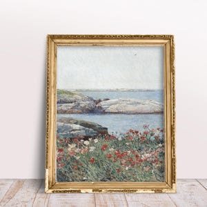 Puede incluir: Una pintura enmarcada de un paisaje mar&iacute;timo con una costa rocosa y un campo de flores rojas en primer plano. El cielo es de un azul claro y el agua es de un azul verdoso claro.