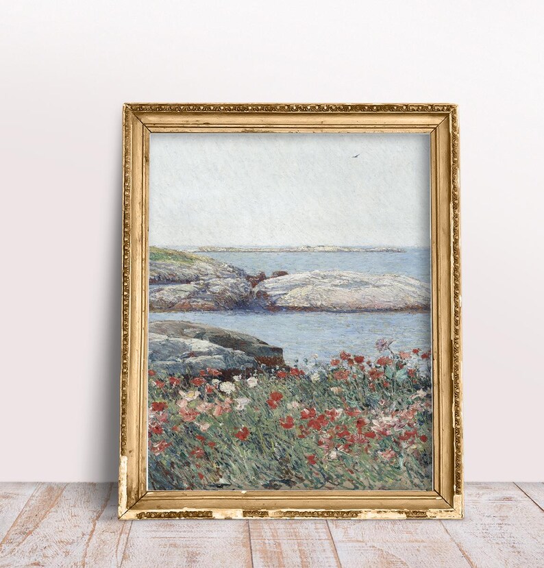 Puede incluir: Una pintura enmarcada de un paisaje mar&iacute;timo con una costa rocosa y un campo de flores rojas en primer plano. El cielo es de un azul claro y el agua es de un azul verdoso claro.