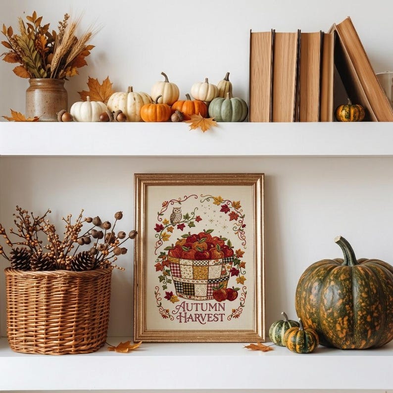 May include: A framed print featuring a basket of red apples, an owl, and autumn leaves with the text "AUTUMN HARVEST" in a gold frame. The print is displayed on a shelf with a wicker basket of dried branches and various pumpkins and gourds.