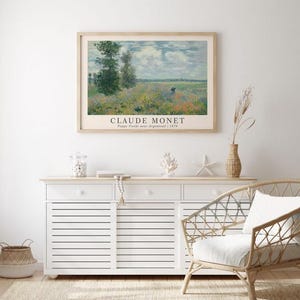 May include: A framed print of a painting by Claude Monet titled "Poppy Fields near Argenteuil" from 1875. The painting depicts a field of poppies with a blue sky and white clouds in the background.
