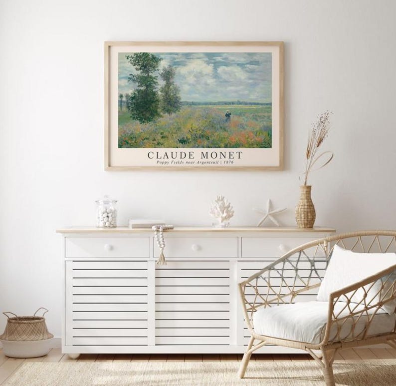 May include: A framed print of a painting by Claude Monet titled "Poppy Fields near Argenteuil" from 1875. The painting depicts a field of poppies with a blue sky and white clouds in the background.