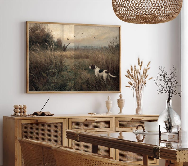Peut inclure: Tableau vintage encadr&eacute; repr&eacute;sentant une sc&egrave;ne de chasse avec un chien dans un champ. L'&oelig;uvre d'art est encadr&eacute;e dans un cadre en bois marron et dor&eacute;. Le chien est blanc avec des taches marron. L'arri&egrave;re-plan montre un chasseur, des oiseaux et des herbes hautes.