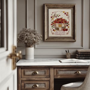 May include: A framed wall art print featuring a basket filled with red apples, surrounded by autumn leaves and a small owl, with the text "AUTUMN HARVEST" printed in red at the bottom. The artwork is displayed in a dark metallic frame.