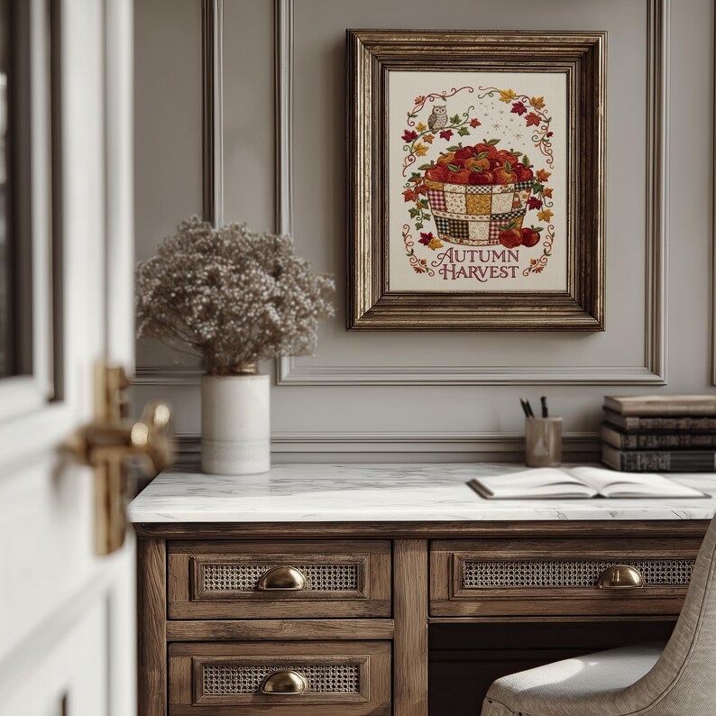May include: A framed wall art print featuring a basket filled with red apples, surrounded by autumn leaves and a small owl, with the text "AUTUMN HARVEST" printed in red at the bottom. The artwork is displayed in a dark metallic frame.