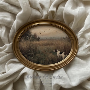 Peut inclure: Impression ovale encadr&eacute;e repr&eacute;sentant une sc&egrave;ne de chasse avec un chien, un chasseur et des oiseaux en vol. L'&oelig;uvre d'art se d&eacute;roule dans un champ avec de hautes herbes et des arbres, encadr&eacute;e par un cadre ovale dor&eacute;. L'impression est pos&eacute;e sur un tissu blanc textur&eacute;.