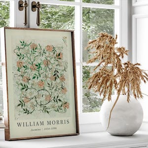 May include: A framed print of a botanical illustration with a white background and green and pink floral designs. The print has the text "William Morris" and "Jasmine | 1834-1896" below the illustration.