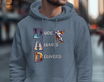 Op de afbeelding: Een blauwe hoodie met de tekst "DAD ALWAYS DELIVERS" in een kleurrijk lettertype. Een superheldenafbeelding staat rechts van de tekst. De hoodie heeft een voorzak en een capuchon met trekkoord.