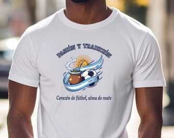 Puede incluir: Camiseta blanca con un gráfico que presenta un balón de fútbol, una taza de mate y el texto "Pasión y Tradición" y "Corazón de fútbol, alma de mate". El diseño incluye los colores de la bandera argentina.