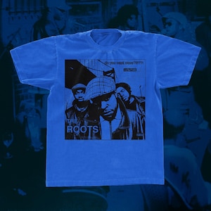 May include: A blue t-shirt with a black and white graphic of the band "The Roots" and their album cover "Do You Want More?!!!".
