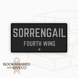 May include: A black and gray sticker with the text "SORRENGAIL FOURTH WING" in white lettering. The sticker is on a background of stacked books.