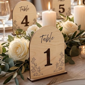 Wooden wedding table number 1 sign made from natural birch plywood, displayed on an elegant wedding reception table with white roses, eucalyptus, candles, wine glasses, and luxury table decor.