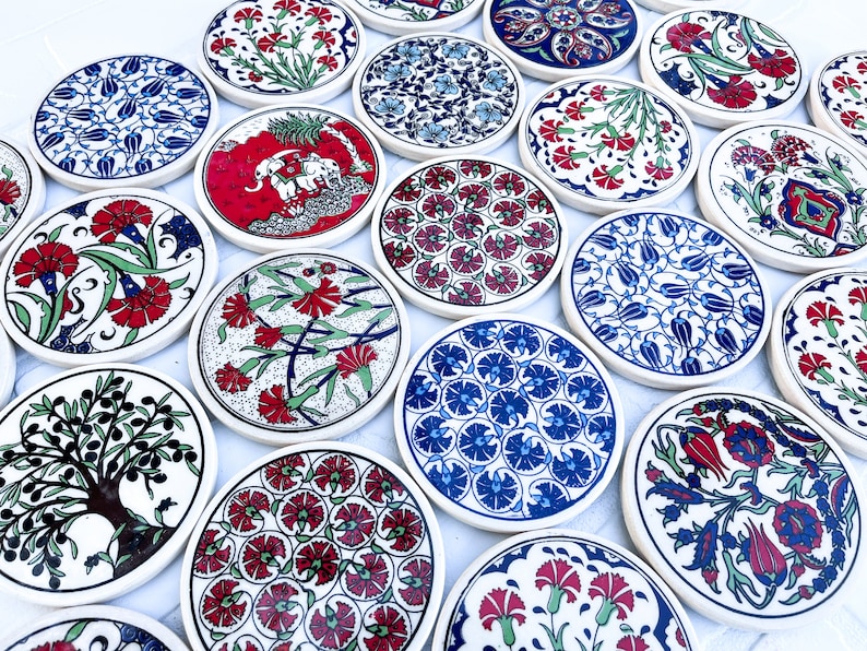 May include: A set of 15 round ceramic coasters with various colorful floral and geometric patterns. The coasters are white with blue, red, and green accents.