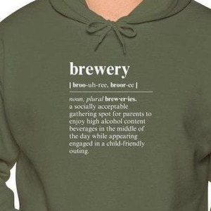 Op de afbeelding: Een groen hoodie met een witte print die het woord "brouwerij" definieert als een sociaal acceptabele ontmoetingsplek voor ouders om te genieten van dranken met een hoog alcoholgehalte in het midden van de dag, terwijl ze zich in een kindvriendelijke uitstapje begeven.