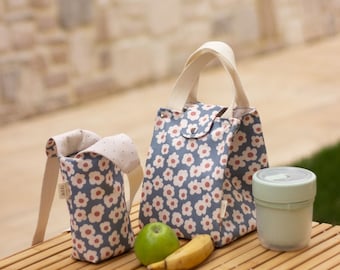 May include: Two floral patterned lunch bags, one large and one small, with a green apple and a banana on a wooden surface. The smaller bag has a white strap with the word "MILK" printed on it.