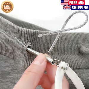 May include: A flexible metal spring tool designed for threading drawstrings through fabric channels. The silver-colored coil features a small loop at one end for attaching a cord, shown here being inserted into the waistband of grey sweatpants.
