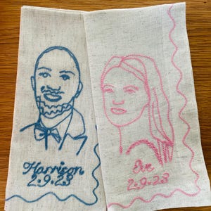 Puede incluir: Dos servilletas de lino con retratos bordados. Una presenta un contorno azul de un hombre con el nombre "Harrison" y la fecha "2.9.23". La otra tiene un contorno rosa de una mujer con el nombre "Eve" y la fecha "2.9.23".