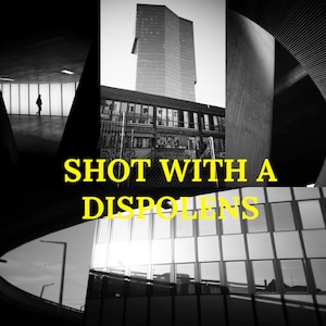 以下が含まれることがあります： 高い建物と黄色い文字「SHOT WITH A DISPOLENS」が書かれた都市の風景の白黒写真です。