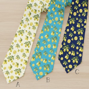 May include: Three neckties with a lemon pattern. The ties are in cream, light blue, and navy blue. Each tie features a repeating pattern of lemons and leaves.