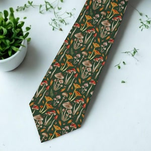 May include: A dark green necktie featuring a repeating pattern of various mushrooms in shades of brown, orange, and red. The tie displays a detailed botanical illustration style with clusters of fungi and small leaves scattered across the fabric.