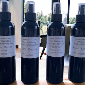 May include: Four black spray bottles with white labels. Each bottle contains 237 ml of odour eliminating linen and upholstery spray. The scents are Cocoa Butter Cashmere, Baja Cactus, Wildflower Whispers, and Fresh Laundry.