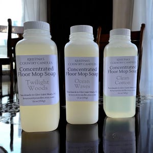 May include: Three bottles of concentrated floor mop soap from Kristina's Country Candles. Each bottle has a white label with the product name and scent: Twilight Woods, Ocean Waves, and Clean Cotton. Each bottle contains 16 oz (454g) of soap.