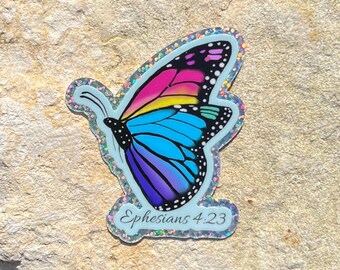 May include: A colorful butterfly sticker with a rainbow wing design, featuring pink, yellow, and blue hues. The sticker has a glittery border and the text "Ephesians 4:23".