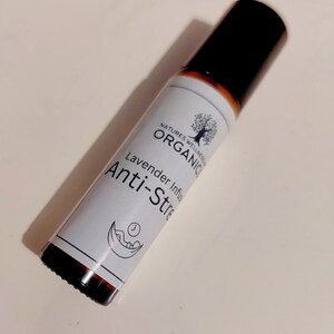 May include: A brown glass roller bottle with a black cap. The label is white with black text that reads "Natures Wellness Organic Lavender Infused Anti-Stress".