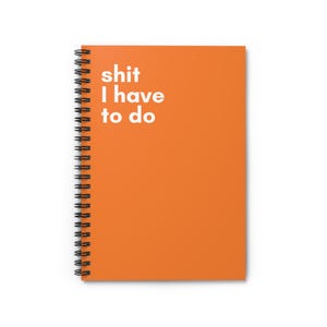 May include: An orange notebook with a black spiral binding. The cover features the white text "shit I have to do". The notebook is a practical item for note-taking and planning.