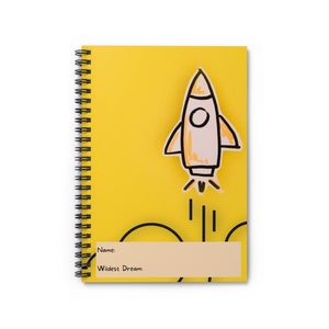 May include: Yellow spiral-bound notebook with a hand-drawn rocket ship graphic. The rocket is white with orange accents and black outlines. The notebook has a space for the name and the text "Wildest Dream:" printed on it.