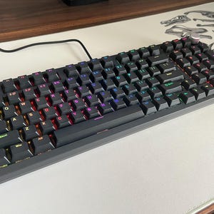 Könnte beinhalten: Eine weiße Keramik-Tasse mit schwarzem Henkel und dem Text "But First, Coffee" in handschriftlichem Stil. Die Tasse fasst wahrscheinlich 325-440 ml, ideal für ein Morgengetränk.