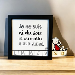 Peut inclure: Un cadre noir avec l'inscription "Je ne suis ni du soir, ni du matin. JE SUIS DU WEEK-END." Le cadre contient une liste des jours de la semaine en bas. Un autocollant d'un personnage bâton est à droite.