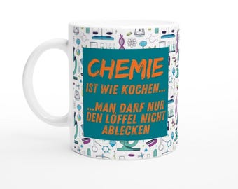 May include: White ceramic mug with a teal blue and orange design. The mug features a science-themed pattern with various chemical symbols and lab equipment. The text on the mug reads "Chemie ist wie kochen... ...man darf nur den Löffel nicht ablecken."